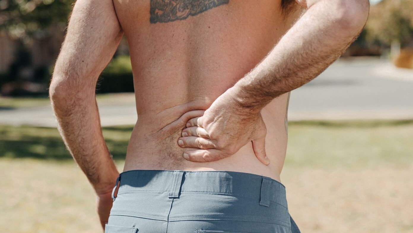 Man holding his lower back from sciatica and low back pain, One80 Chiropractic in Omaha, NE